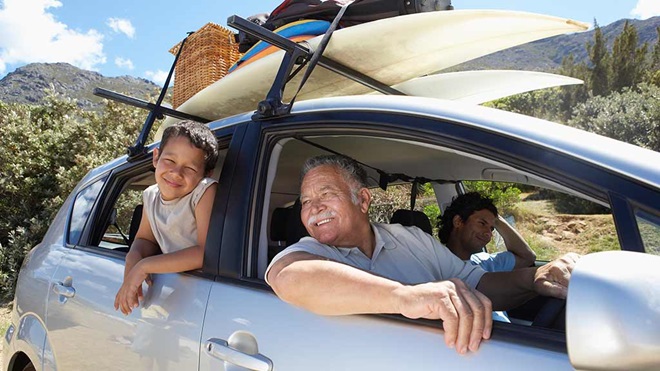 family in car with surfboards strapped to roof